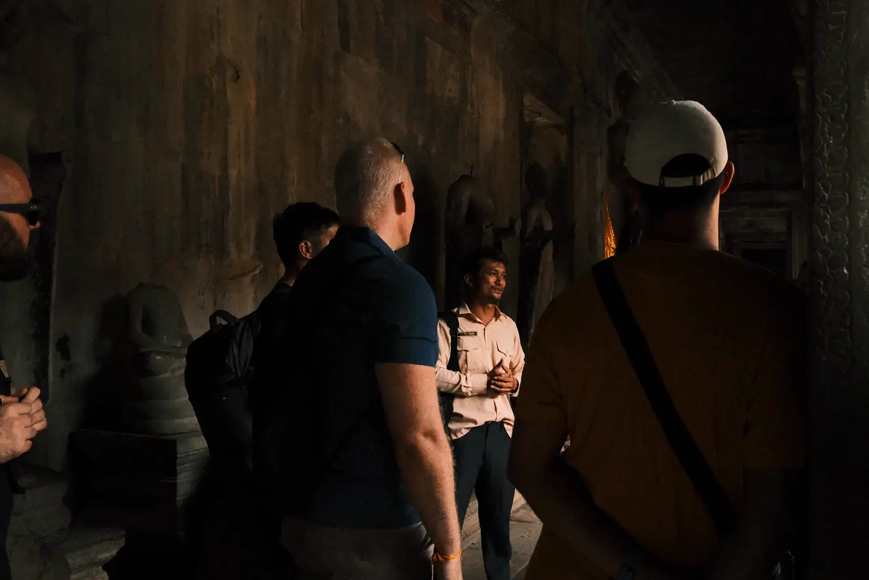 Un grupo de viajeros conversando en un pasillo en penumbra de Angkor Wat