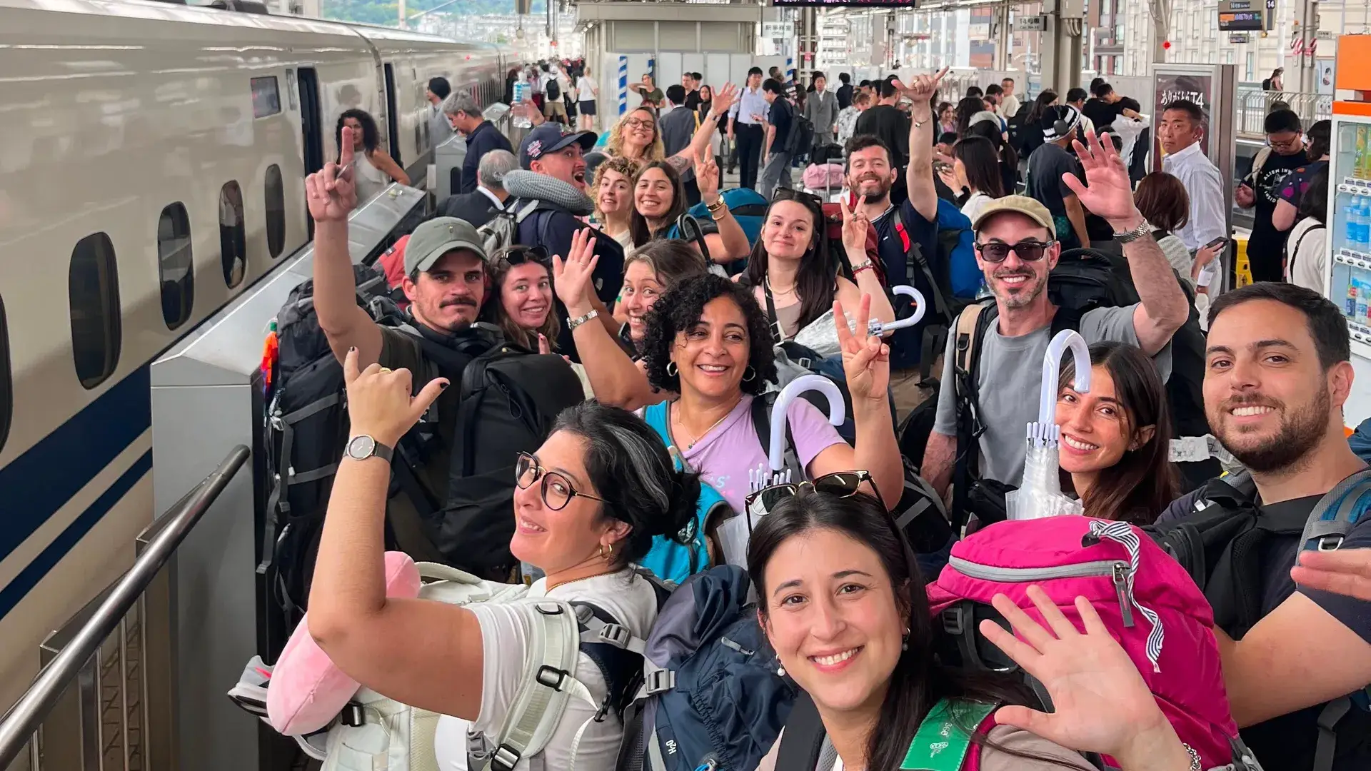 Grupo saludando en el andén del tren bala, en Japón