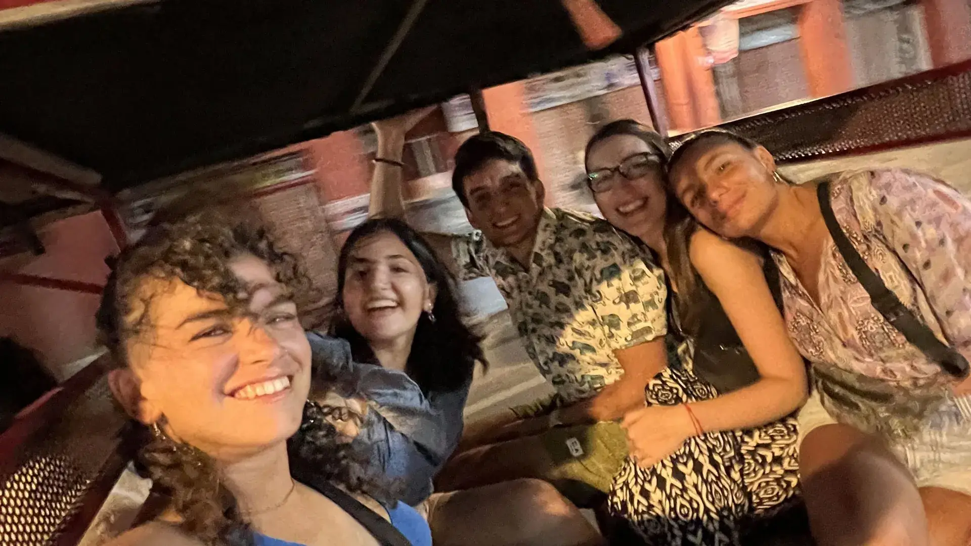 Cinco viajeros apretados en un tuk-tuk, de noche