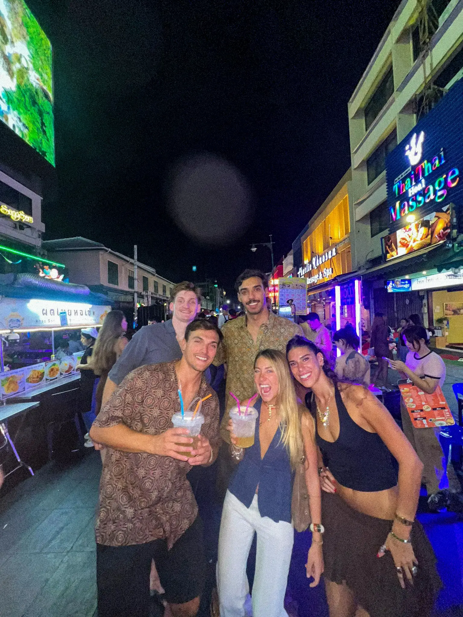 Cuatro viajeros de noche en la Khao San Road, entre los carteles de neón