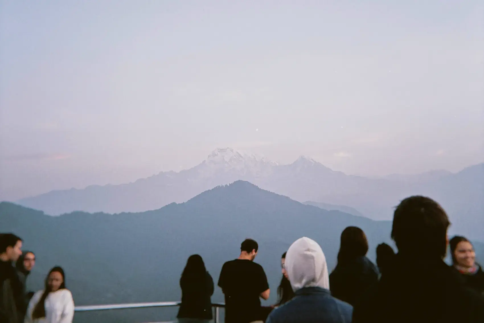 Siluetas de personas mirando la montaña nevada al atardecer
