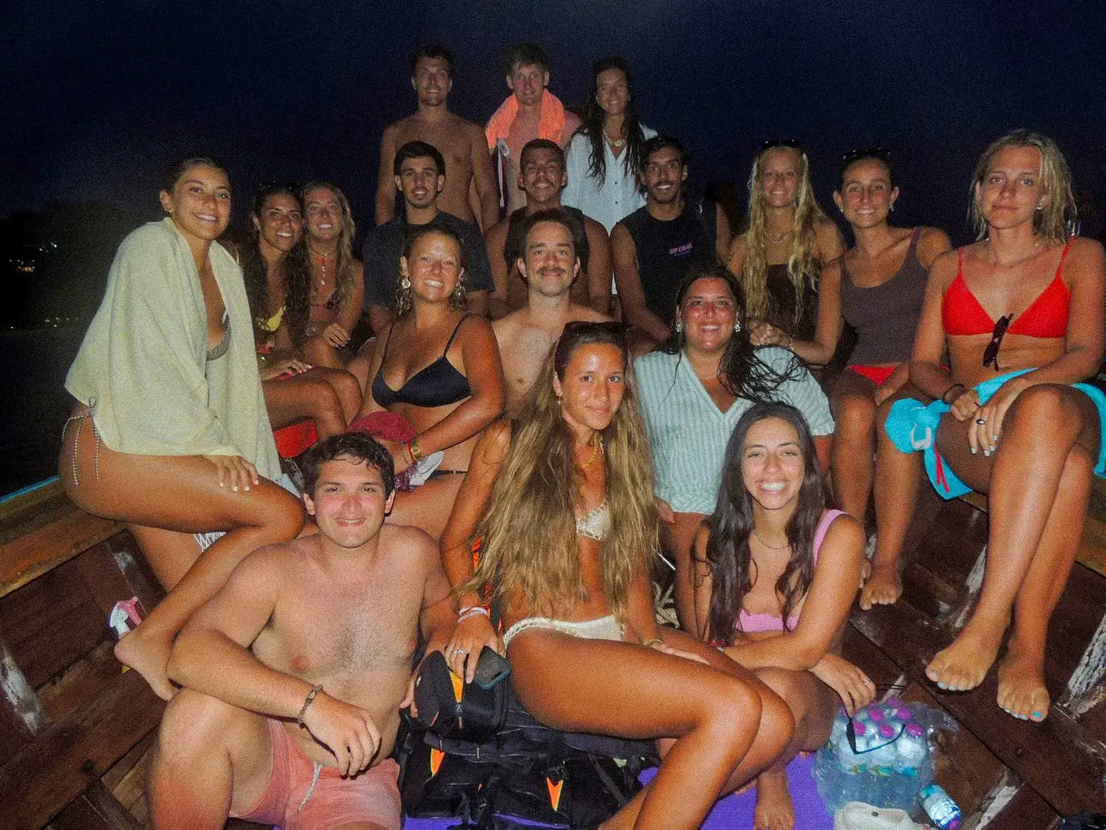 El grupo entero de noche en la cubierta de un barco, iluminados por luces de colores