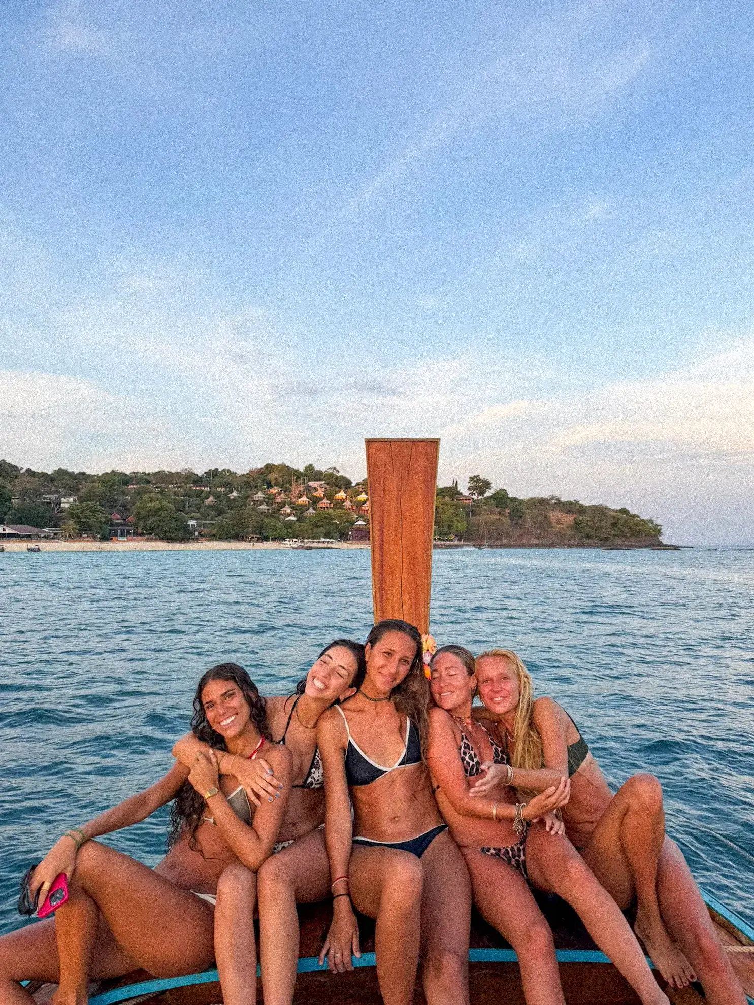 Cuatro viajeras sentadas en la proa de un barco, con el mar de Tailandia atrás