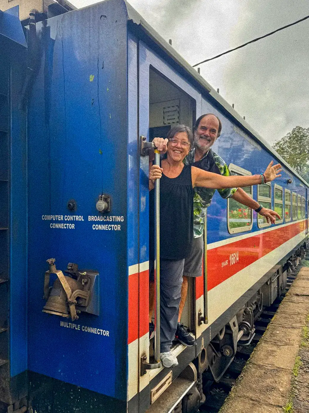 Ro y Marce asomados a la ventanilla de un tren azul de Sri Lanka